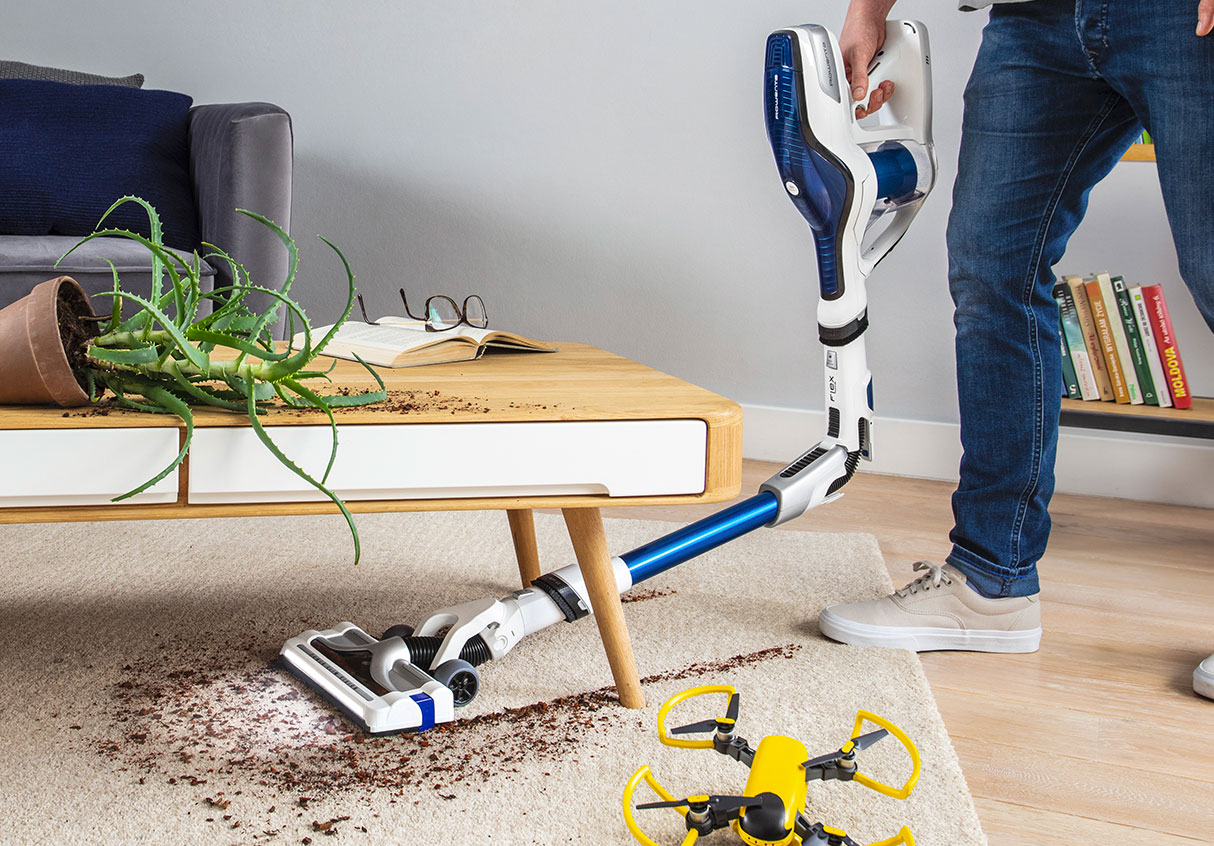 Man vacuuming under a brown table